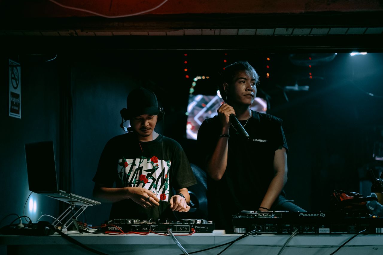 Home Two DJs performing with equipment in a vibrant nightclub setting, exuding party vibes.