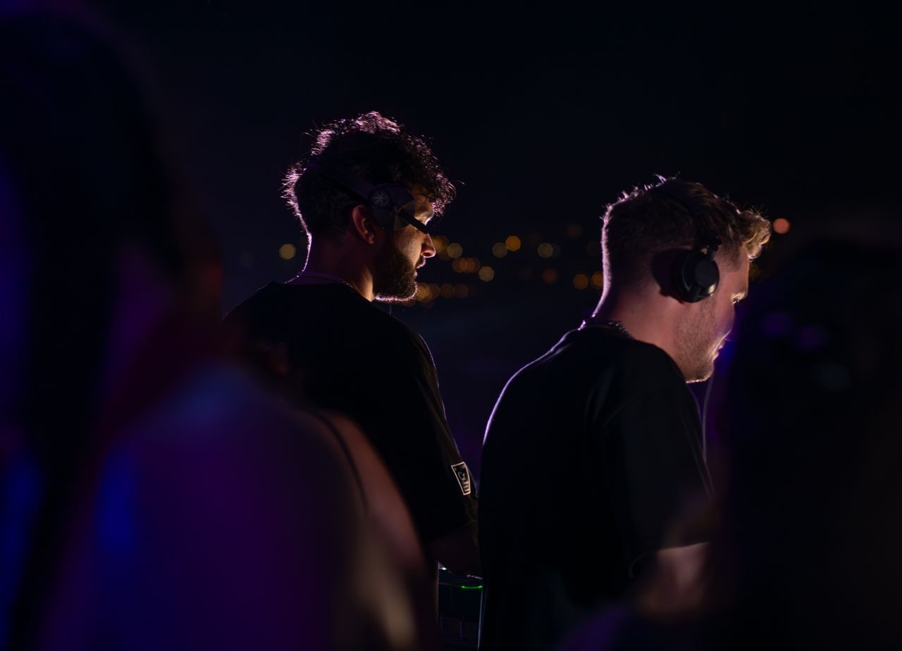 Home Two DJs wearing headphones performing at a nighttime event in Sozopol, Bulgaria.