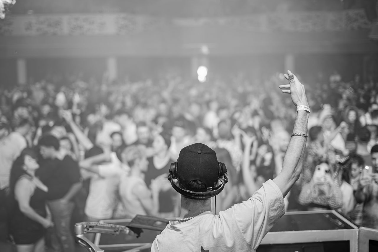 Services DJ in control, hyping up a large crowd at a lively nightclub event, creating an electrifying atmosphere.