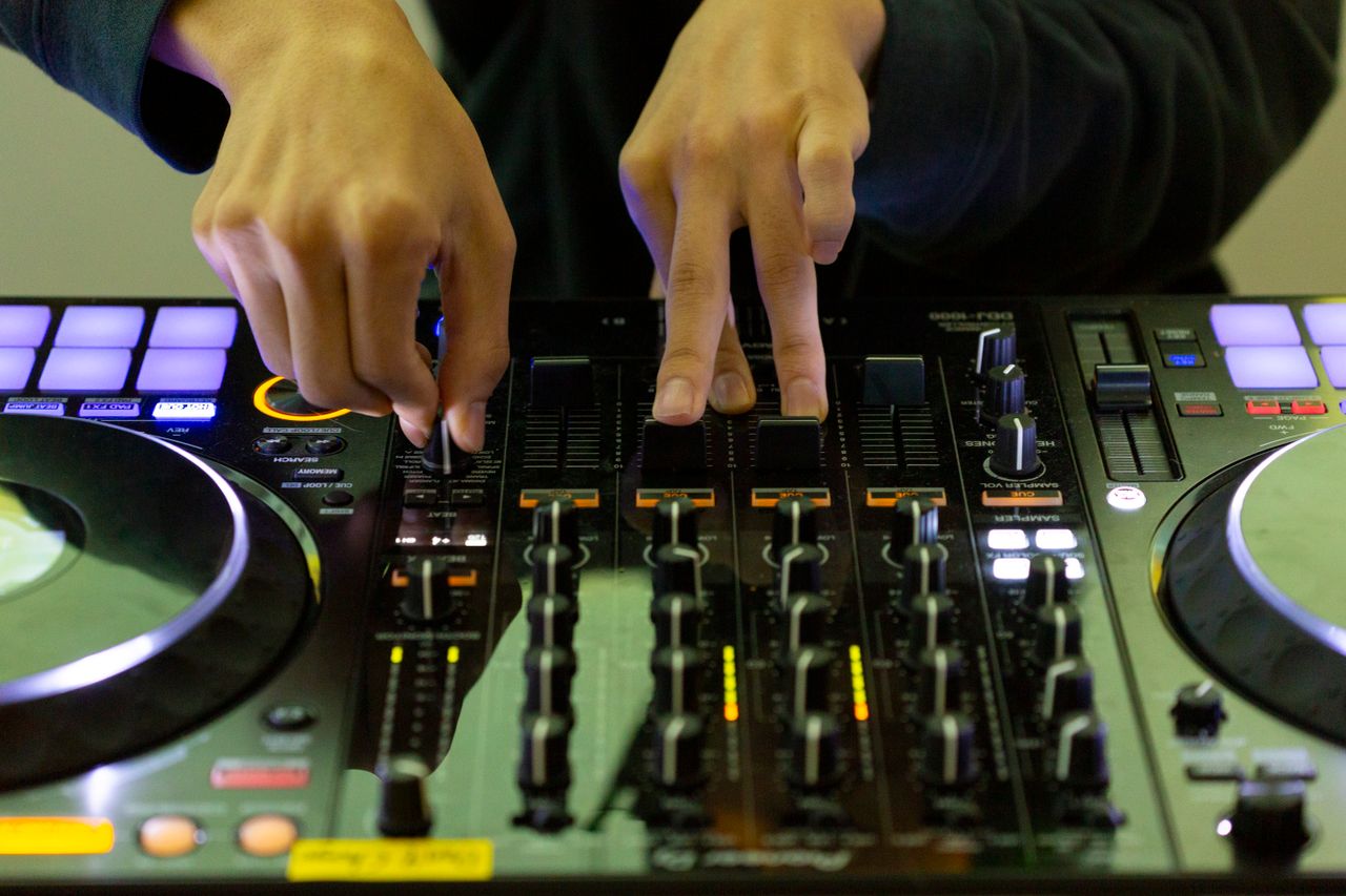 Home Close-up of DJ's hands mixing music on a turntable, highlighting electronic skill and nightlife.
