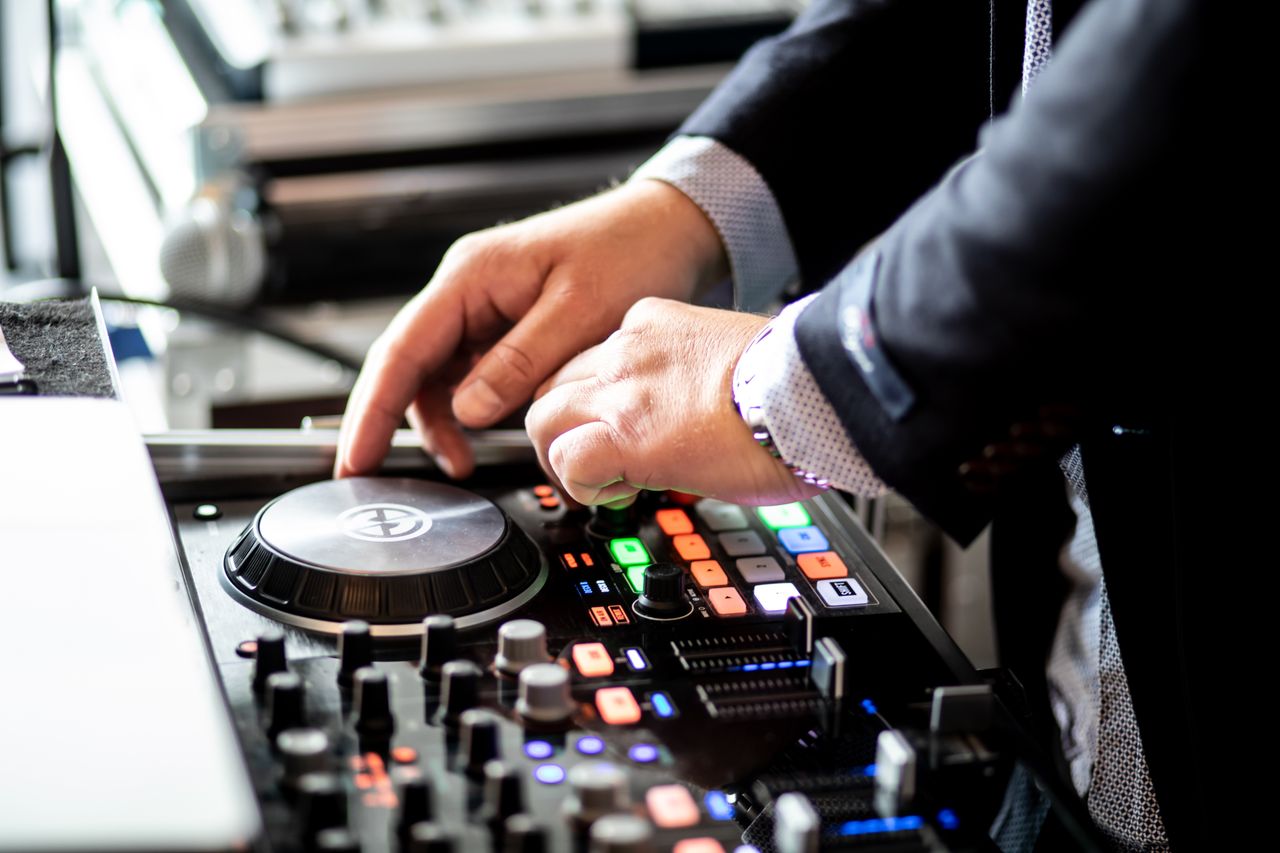 Services Unrecognizable male musician standing near table with audio console and touching turntable while performing record in modern studio during daytime